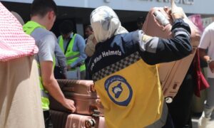 A volunteer in the Syria Civil Defence assists Syrian pilgrims in transporting their luggage - May 25, 2025 (Syria Civil Defence)